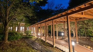 A covered outdoor area with wooden beams and a pathway. - Mori No Izumi (Ito)