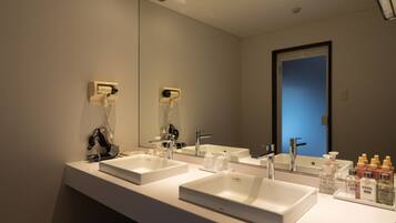 Un baño moderno con dos lavamanos, un espejo grande y una puerta que da a otra habitación.
