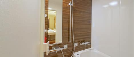 Un baño con tocador de madera, un espejo, una bañera blanca y un cabezal de ducha.