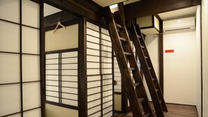 A room with a traditional sliding door, a wooden ladder, and an air conditioning unit. - Guesthouse Nin-jin - Hostel (Niigata)