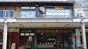 A traditional Japanese building with a storefront, wooden beams, and a bicycle parked outside. - Guesthouse Nin-jin - Hostel (Niigata)