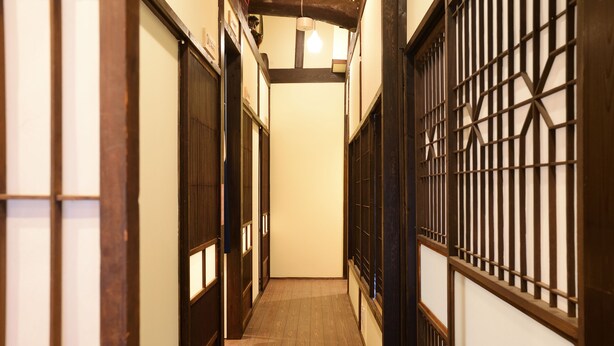 A narrow hallway with wooden flooring and traditional Japanese-style doors and windows. - Guesthouse Nin-jin - Hostel (Niigata)