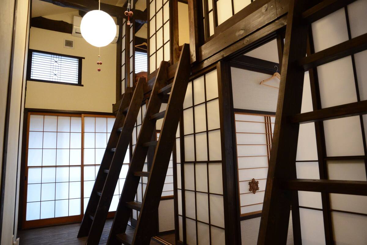 Een traditioneel Japans interieur met tatami vloeren, schuifdeuren en een houten ladder.