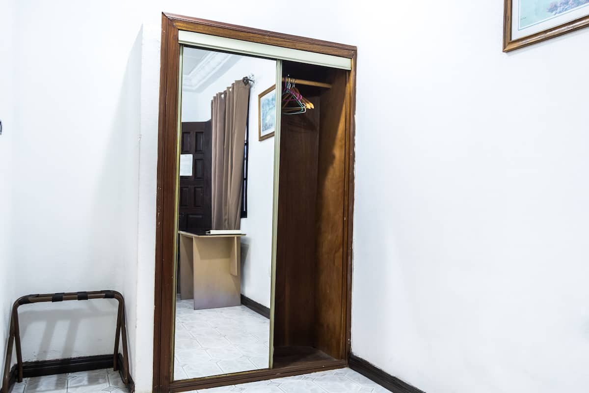 A narrow hallway with a wooden door leading to a closet. A small step stool is placed against the wall.