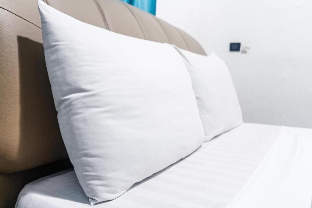 Een bed met witte lakens en een beige hoofdeinde.