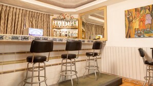 Een bar met drie krukken, een spiegelwand en een plank met flessen.
