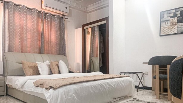 Een slaapkamer met een bed, nachtkastje, stoel, een kamerbreed tapijt en een kledingkast.