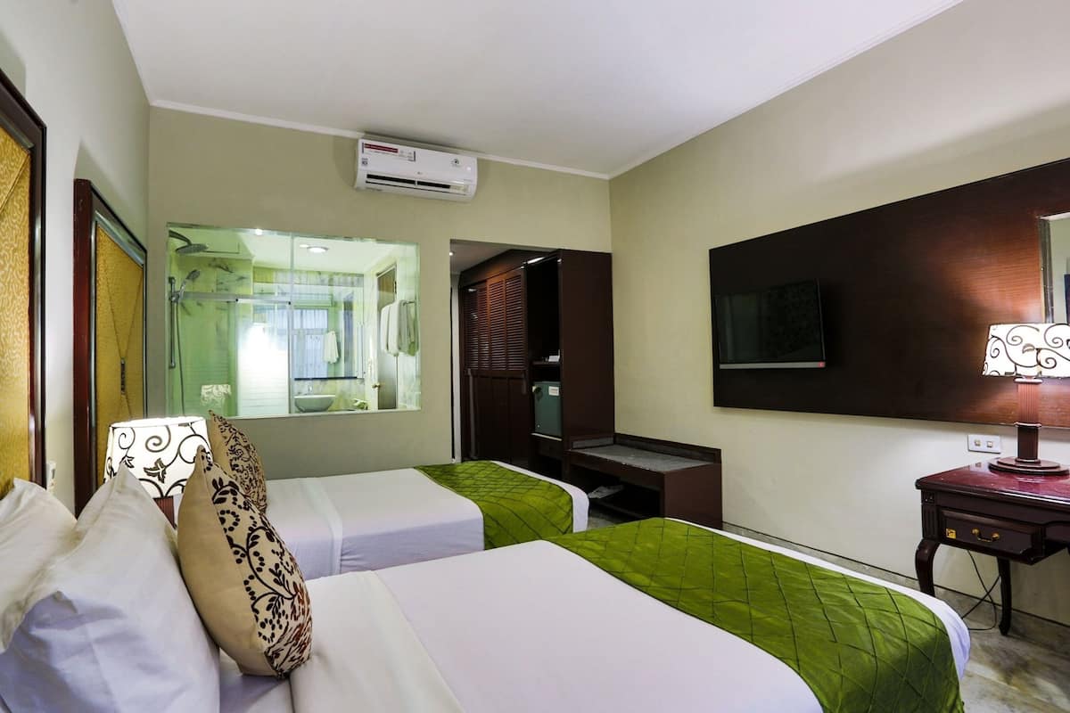 Habitación de hotel con dos camas, un escritorio, un espejo y un equipo de aire acondicionado.