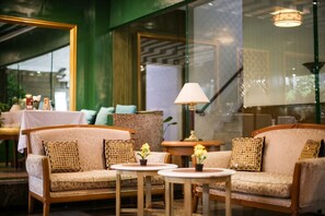 A cozy seating area with cushioned sofas and small tables, each with a potted plant.