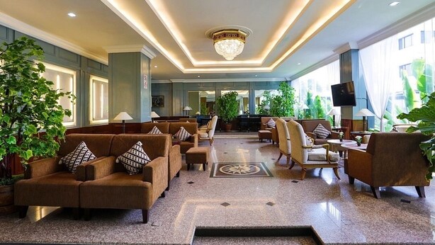 A spacious lobby with a central seating area, large windows, and decorative plants.