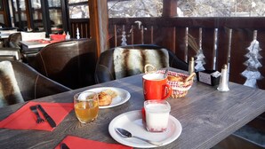 A wooden table with a red napkin, a glass of beer, a plate with pastries, a mug of coffee, and a small basket. - Logis Hôtel et Spa Le Christiania (La Salle-les-Alpes)