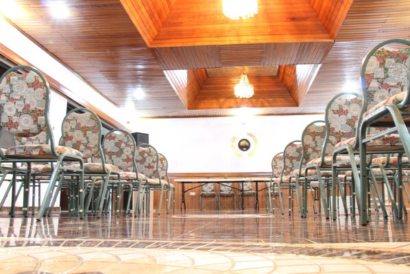 Un salón de conferencias con techo de madera, sillas con diseños y una lámpara de araña.
