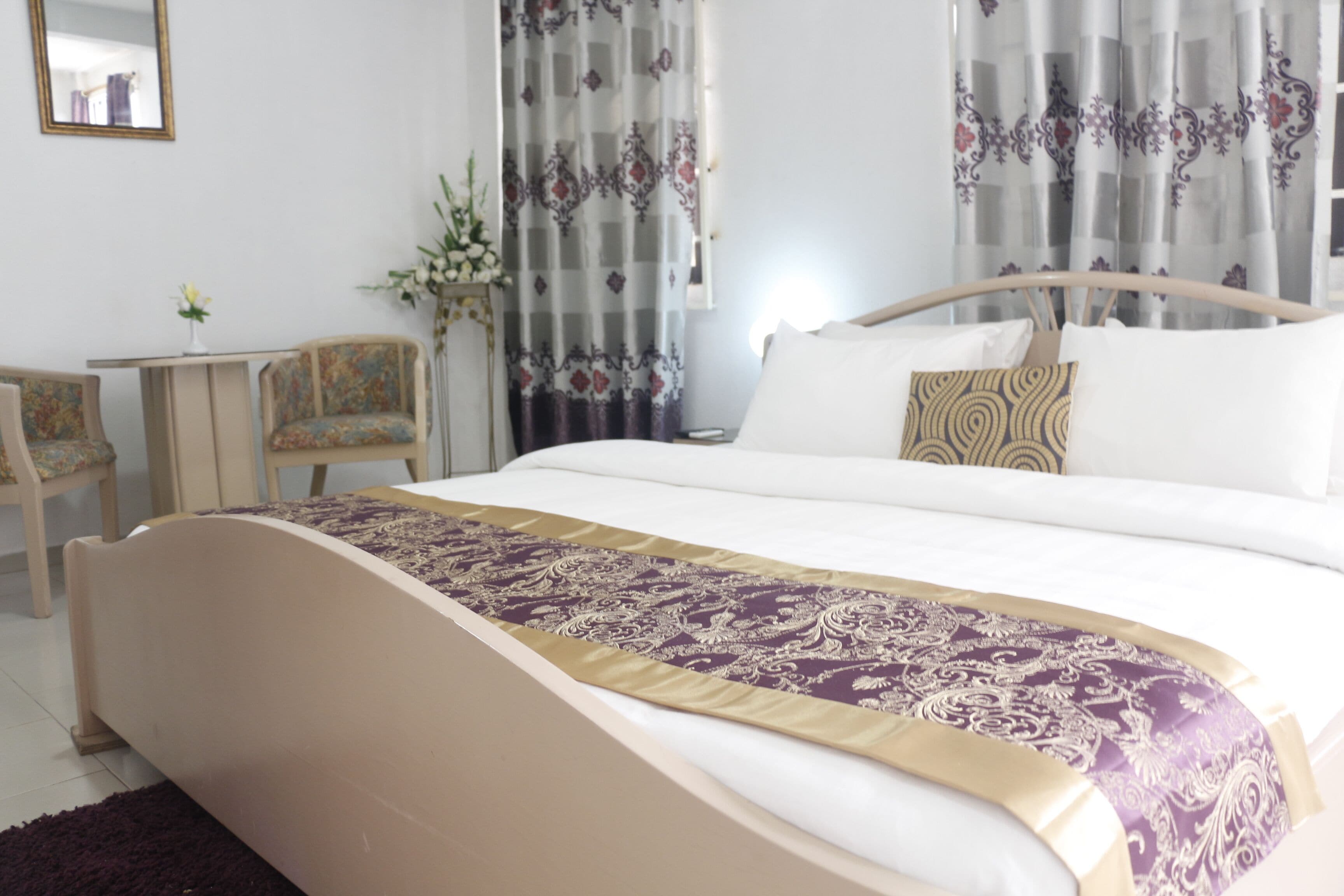 A hotel room with a large bed, a desk, and two chairs.