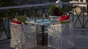 A terrace with white wicker furniture, a glass table, and potted plants. - Hill View Hotel McCarthy Hills (Mallam)