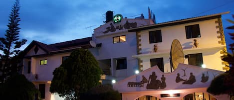 A hotel with a gym room, satellite dish, and outdoor seating area.