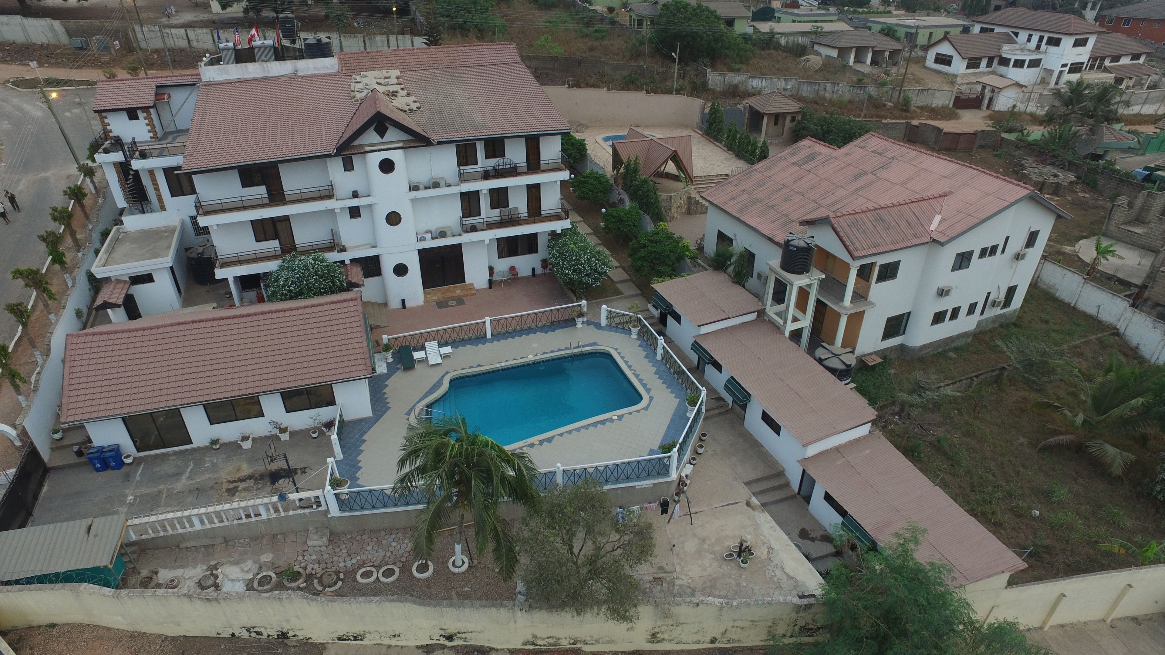 Zona residencial com um edifício grande, com várias varandas, uma piscina e um pequeno jardim.
