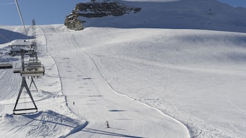 Pista de esquí cubierta de nieve, con un telesilla y una cima montañosa al fondo.