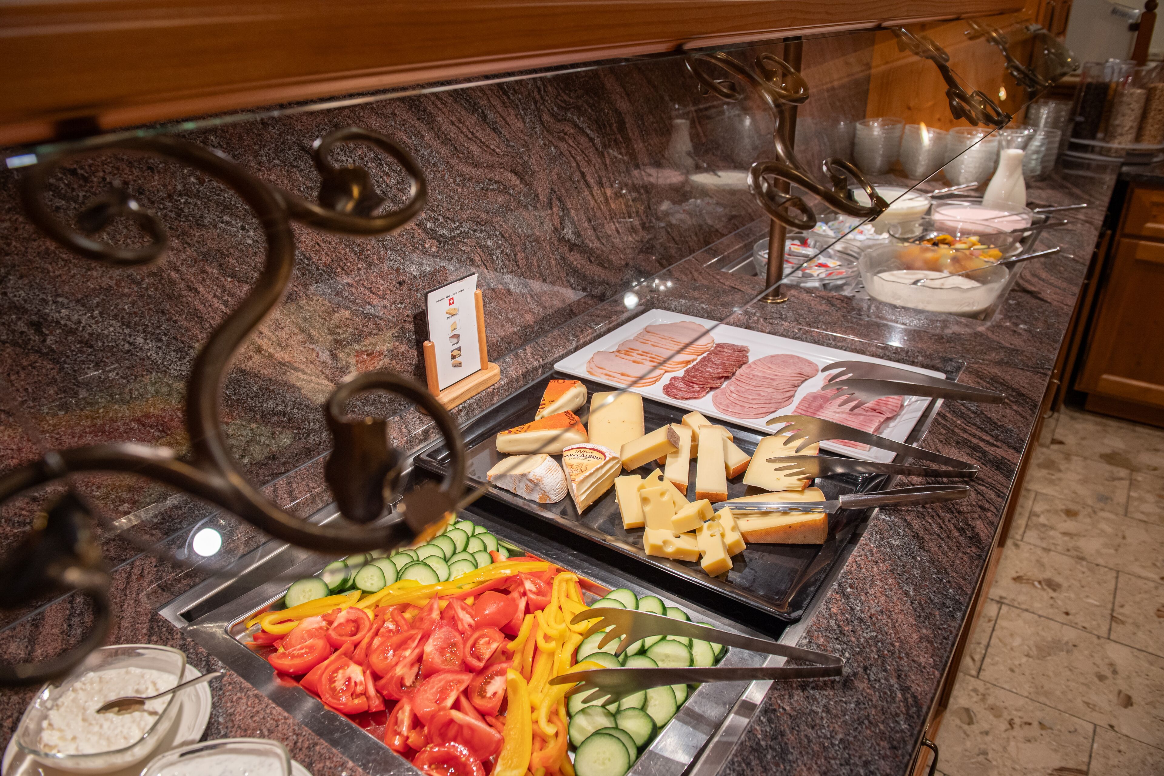 Un buffet proposant une variété de plats, notamment des viandes et fromages en tranches, ainsi que des légumes frais.