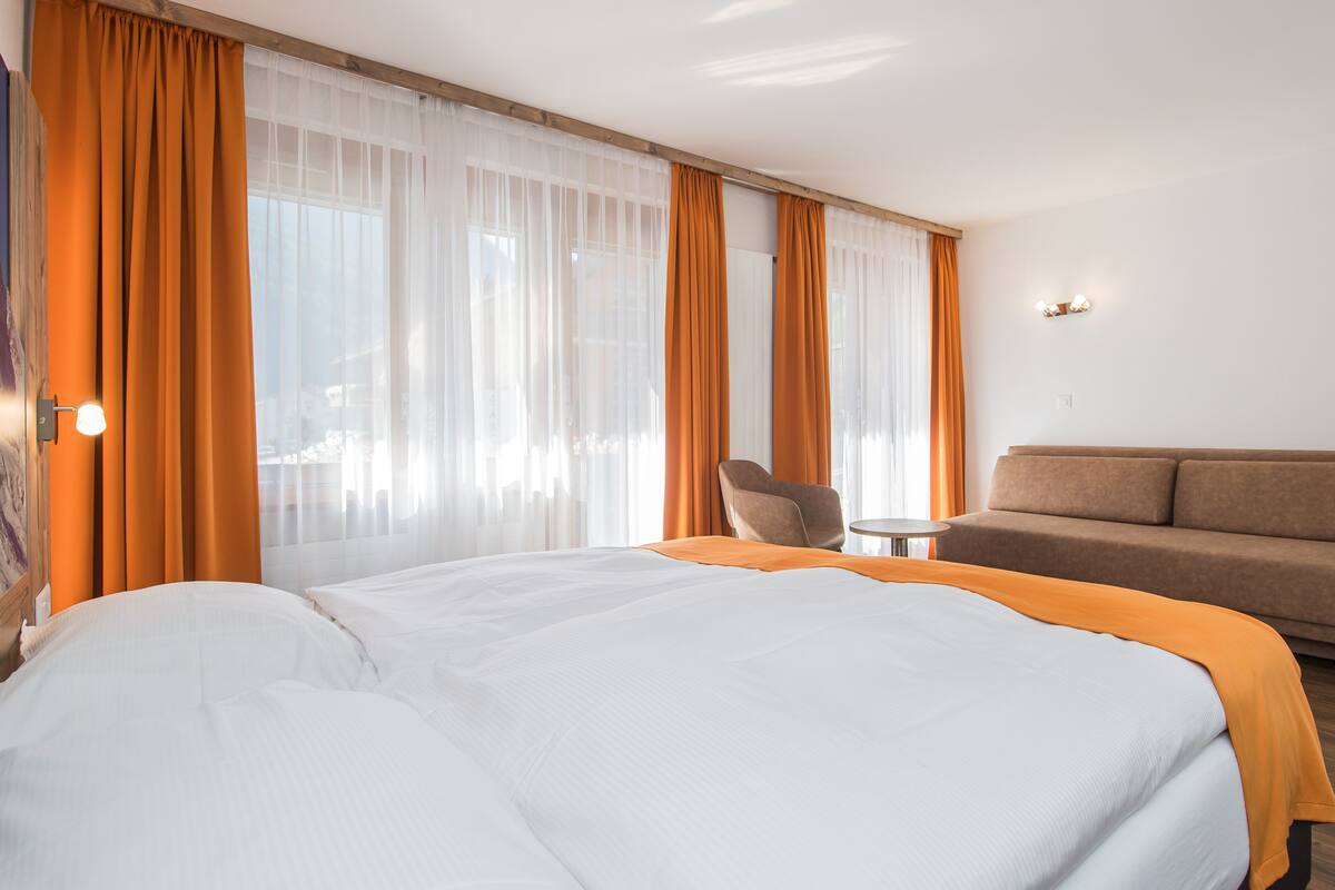 A hotel room with a large bed, a sofa, and a chair.