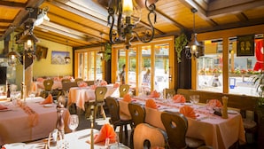 Een restaurant met meerdere tafels klaar voor gasten, met een rustiek houten interieur en grote ramen.