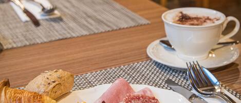 A breakfast setting with a plate of food, a cup of coffee, and cutlery on a table.