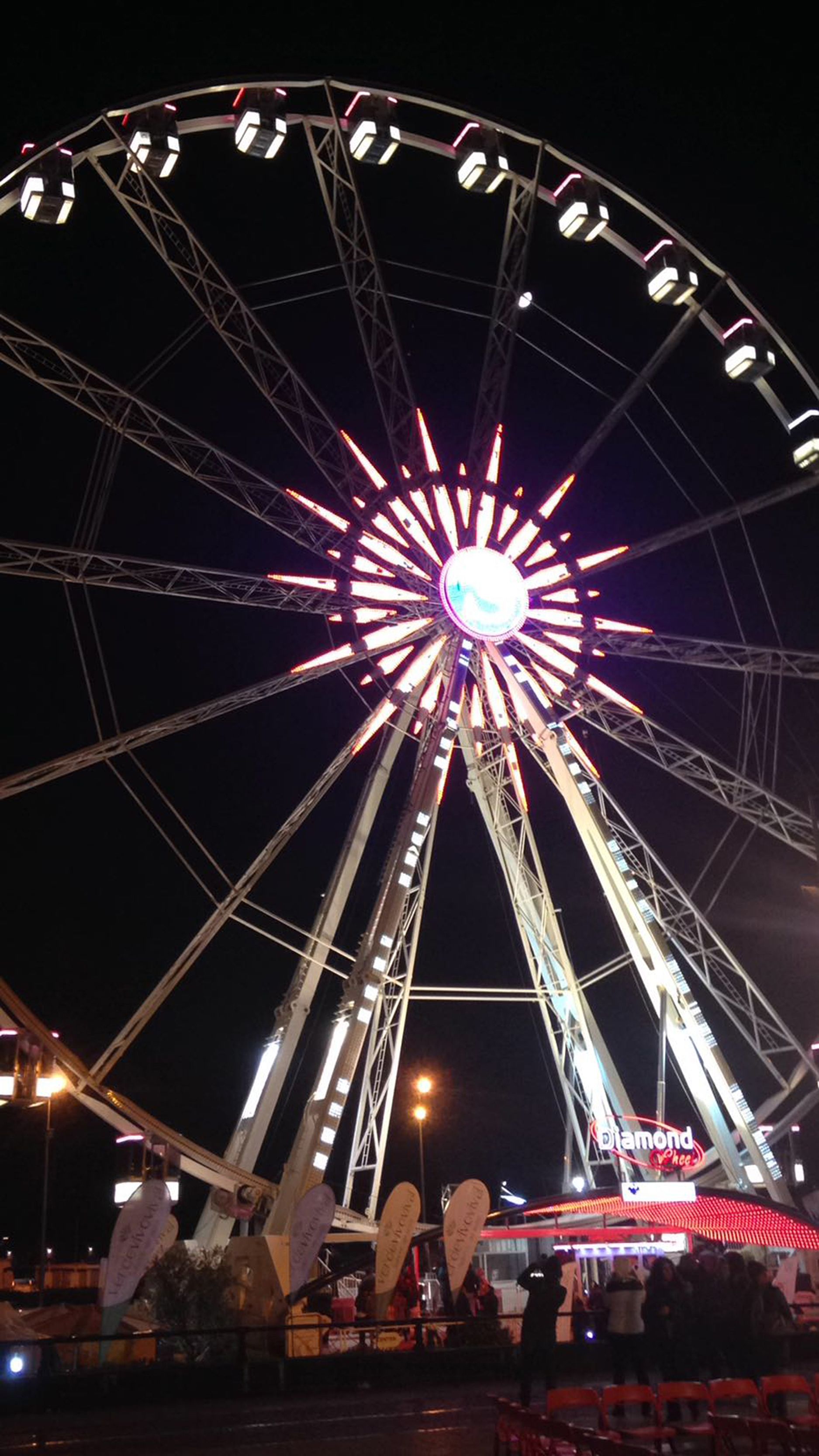 Una ruota panoramica con una luce centrale luminosa e un cartello con su scritto "Diamond Voche".