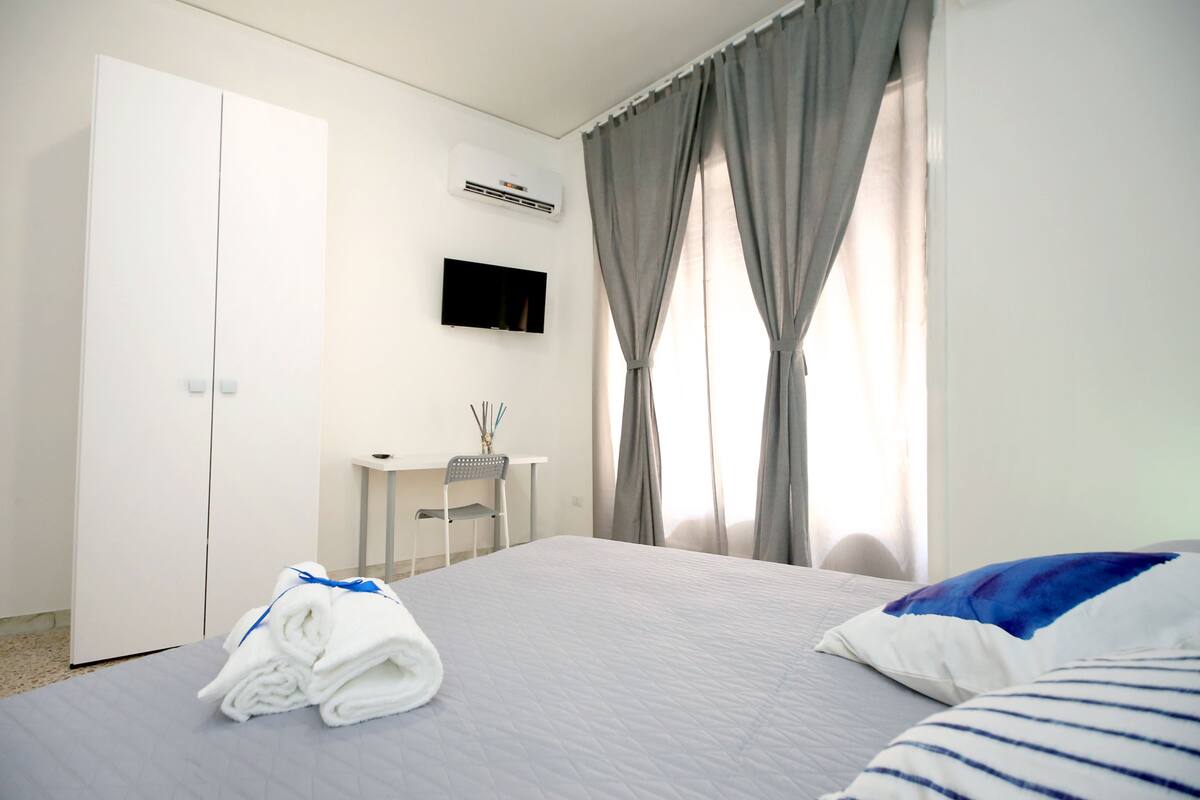 A hotel room with a bed, a desk, a TV, and a wardrobe.