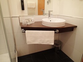 Un bagno con un lavandino bianco, un asciugamano appeso a un portascopevoli e un cestino.