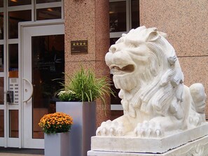 Una estatua de león de piedra frente a un edificio con puerta de cristal.