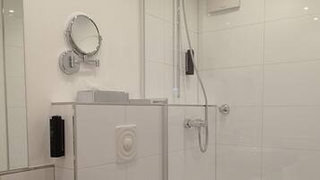 A modern bathroom with a large sink, toilet, and glass-enclosed shower.