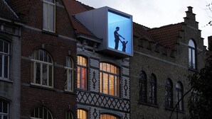 A building with a large digital billboard displaying a silhouette of a man and a child. - Vegan b&b AM/PM (Bruges)