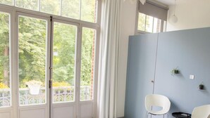 A room with a large window, a blue wall, and two white chairs. - Vegan b&b AM/PM (Bruges)