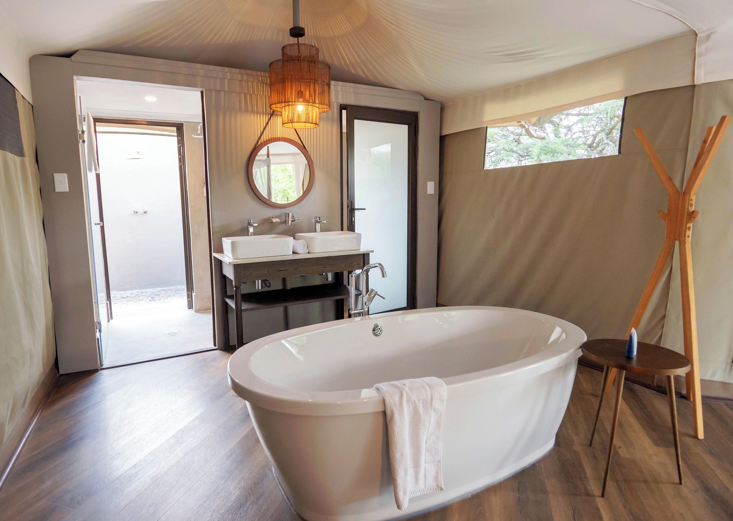 A modern bathroom with a freestanding bathtub, a vanity with two sinks, a large mirror, and a ceiling light fixture.