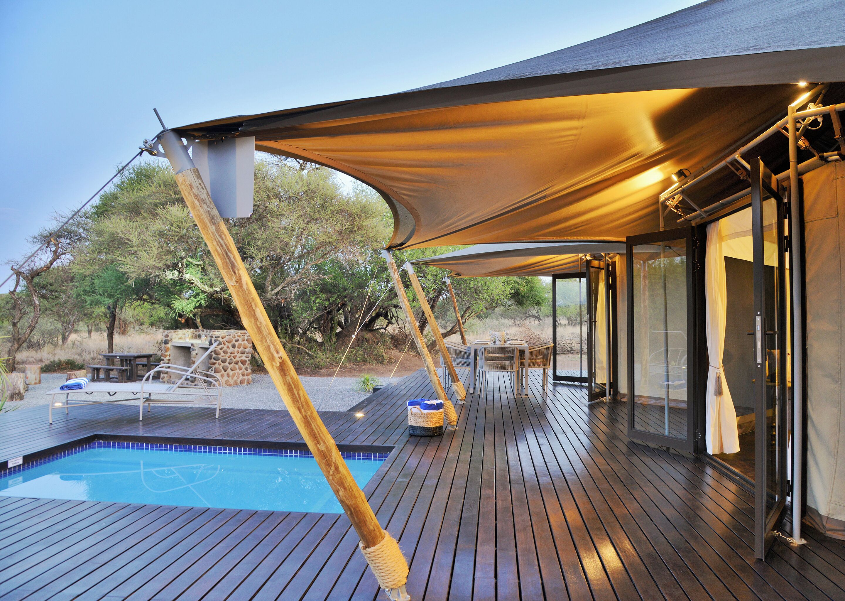 A wooden deck with a pool, outdoor seating, and a canopy providing shade.