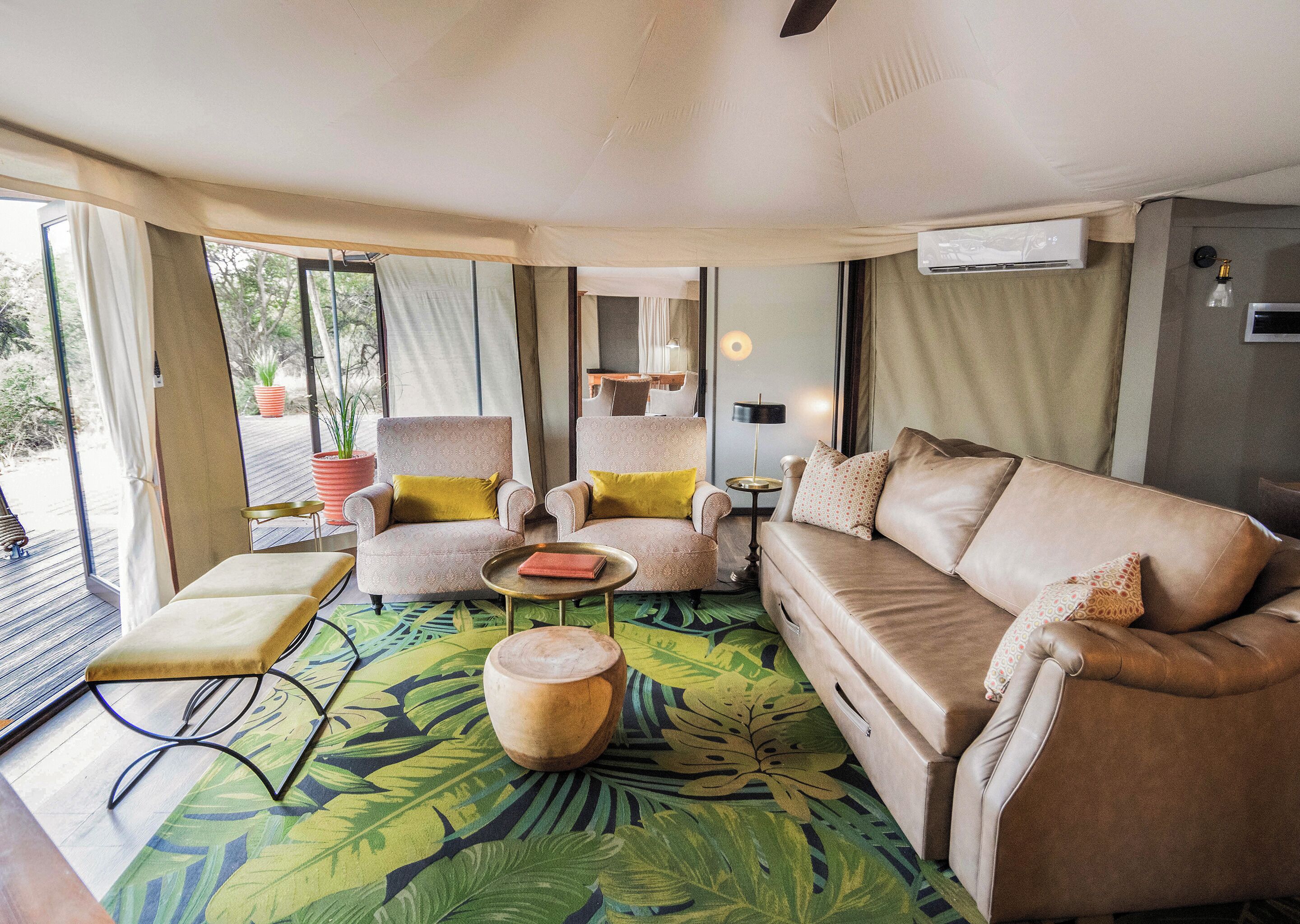 Una habitación con sofá, sillones, una mesita, una planta en maceta y vistas amplias a través de grandes ventanales.