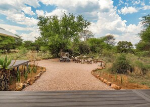 An outdoor seating area with tables and chairs, surrounded by gravel and plants. - Finfoot Lake Reserve by Dream Resorts (Beestekraal)