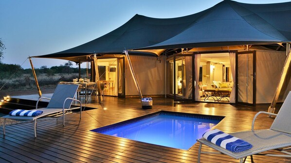 An outdoor swimming pool with lounge chairs, a dining area, and a tented structure. - Finfoot Lake Reserve by Dream Resorts (Beestekraal)