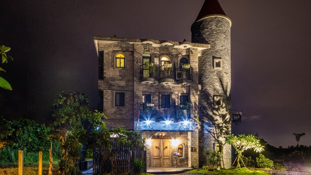 Un edificio histórico con una torre destacada, ventanas arqueadas y una entrada bien iluminada.