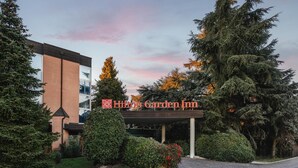 The exterior of the Hilton Garden Inn with a clear view of the building's entrance, a covered walkway, and surrounding greenery. - Green Park Bologna Residence (Granarolo dell'Emilia)