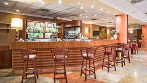 A bar area with a wooden counter, multiple bar stools, and a variety of bottles on shelves. - Green Park Bologna Residence (Granarolo dell'Emilia)