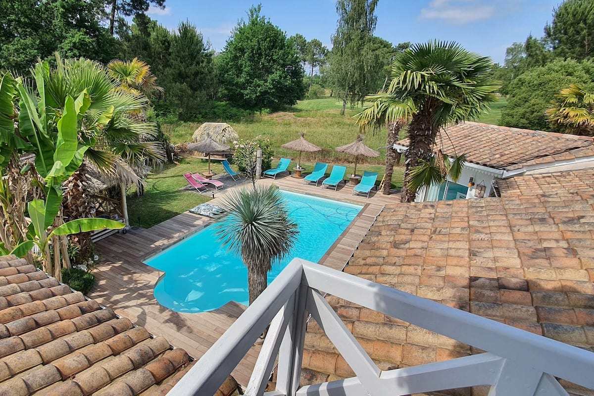 A pool area with lounge chairs and a thatched-roof structure.