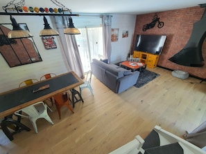 Uma sala de estar com sofá, televisão, lareira e um espaço de jantar com mesa e cadeiras.