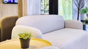 Una sala de estar moderna con un sofá grande, una planta pequeña en maceta y un televisor montado en la pared.