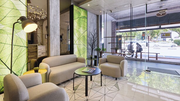 Un lobby moderno con un sofá, sillones, una mesita de centro y un ventanal con vista a la calle.