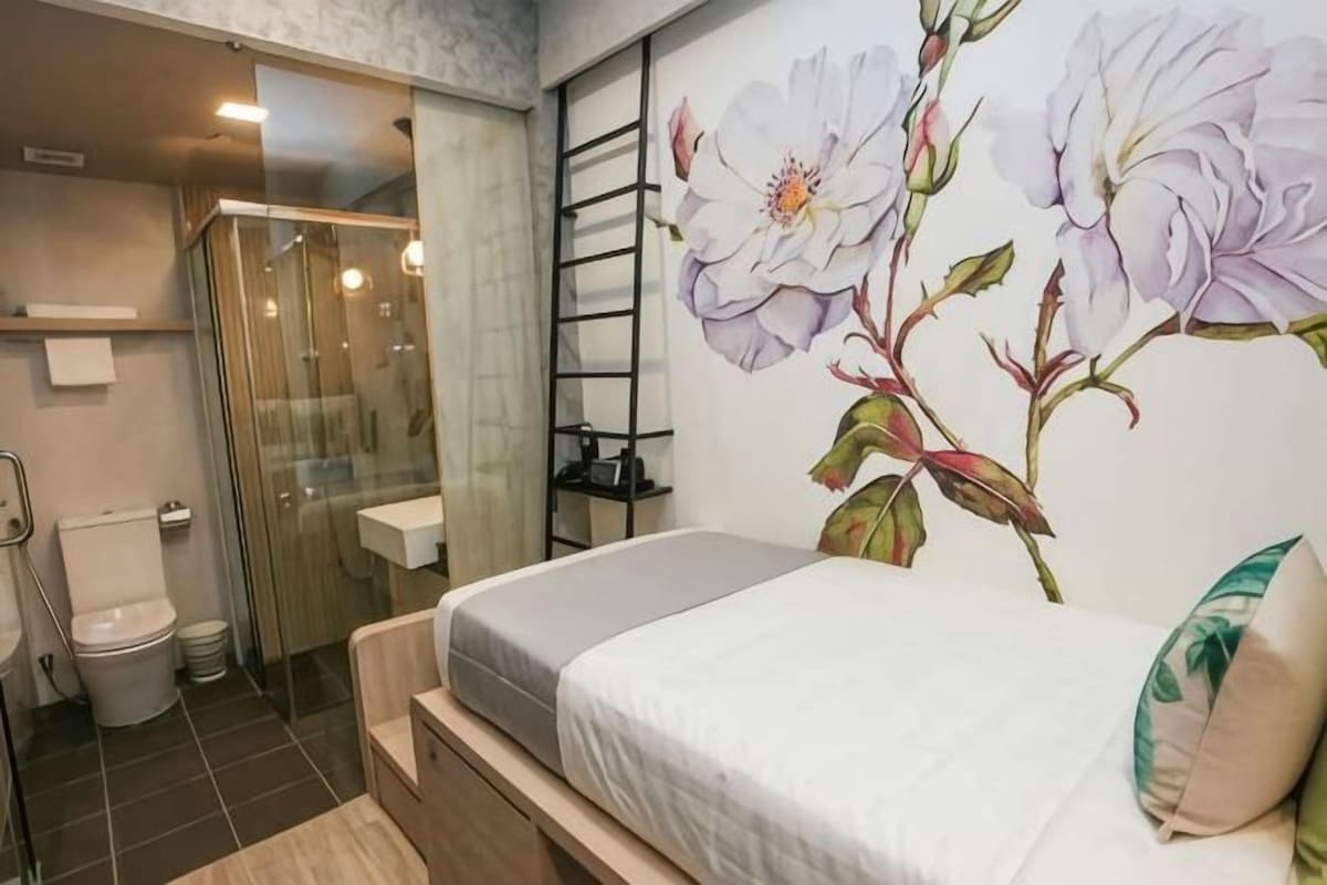 Un dormitorio con cama, ducha, inodoro y un muro con un mural floral.