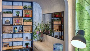 Un interior moderno con estanterías de madera, plantas en macetas y un dispensador grande de agua.