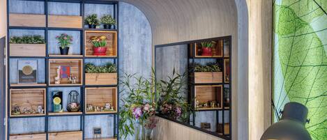 A modern interior with wooden shelves, potted plants, and a large water dispenser.