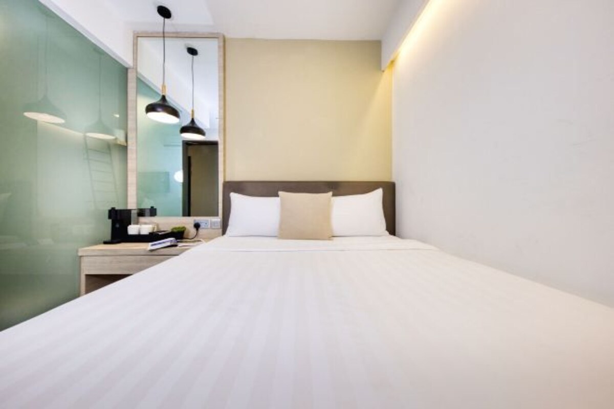Una habitación de hotel con cama, mesita de noche y espejo.