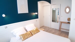 Un dormitorio con cama, mesita de noche, espejo y pared decorada con una piña.