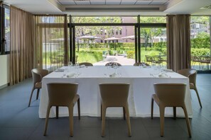 A dining area with a table set for four, large windows, and outdoor seating visible through the glass. - UNA Hotels Bologna Fiera (Bologna)